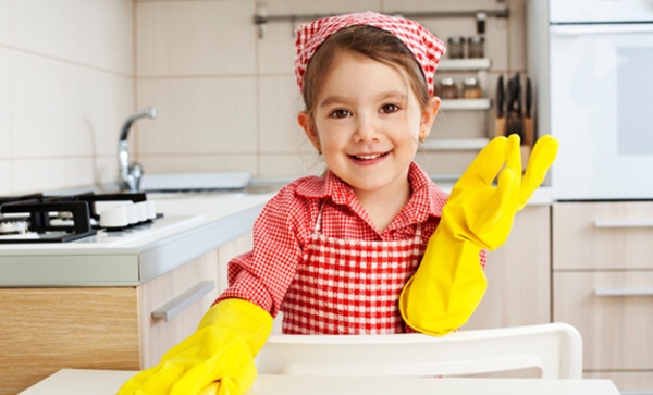 Little Girl holding sponge and smiling in the kitchen